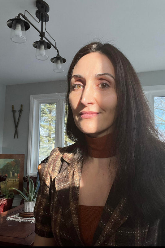 Woman with long dark hair indoors, wearing a patterned jacket.